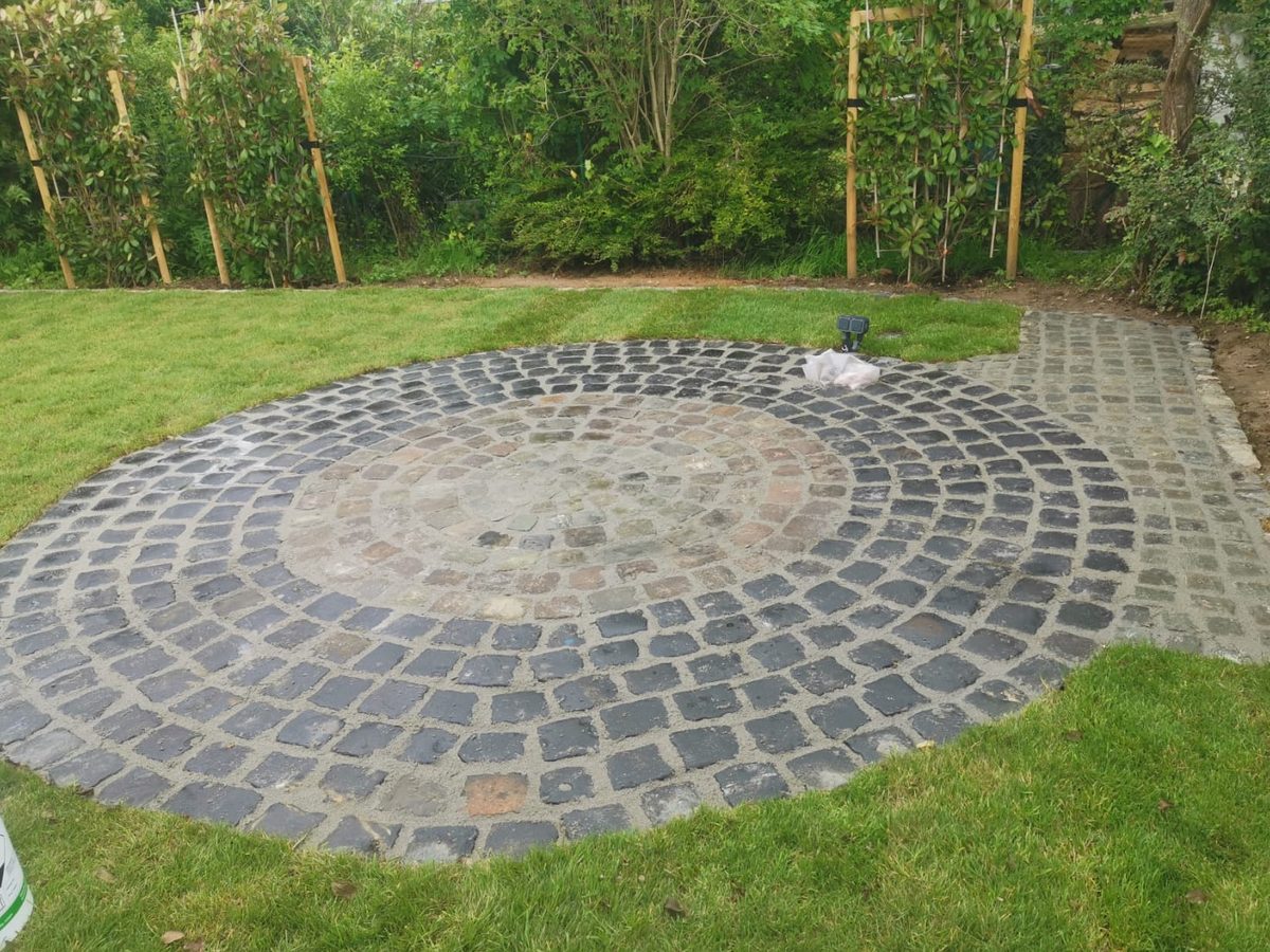 Runder Sitzplatz aus Natursteinpflaster in einer neu angelegten Rasenfläche