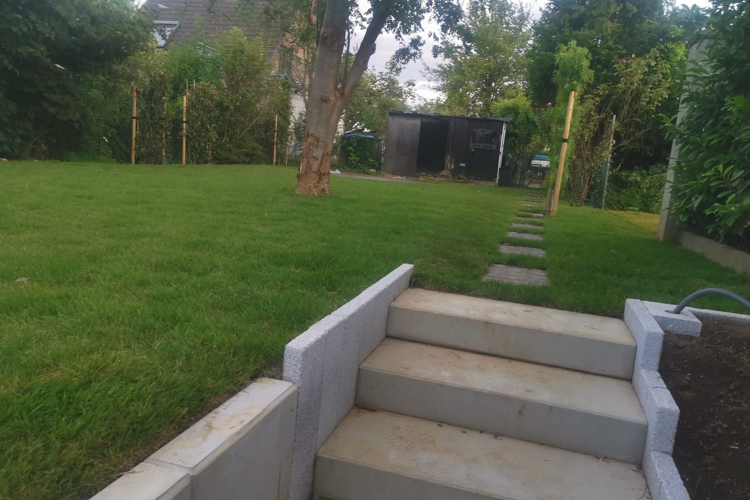 Neu angelegter Garten mit Blockstufen, Rasenfläche und Trittsteinweg